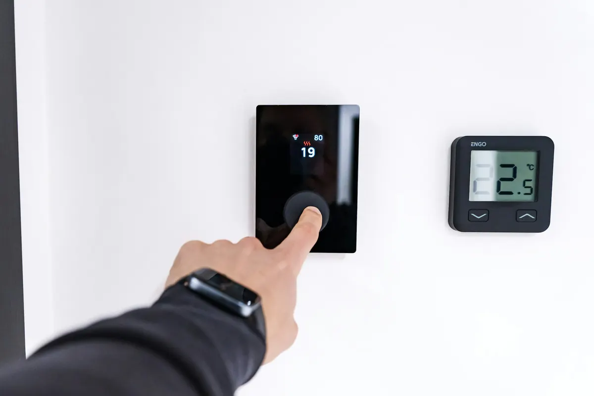 Homeowner adjusting a modern digital thermostat on the wall