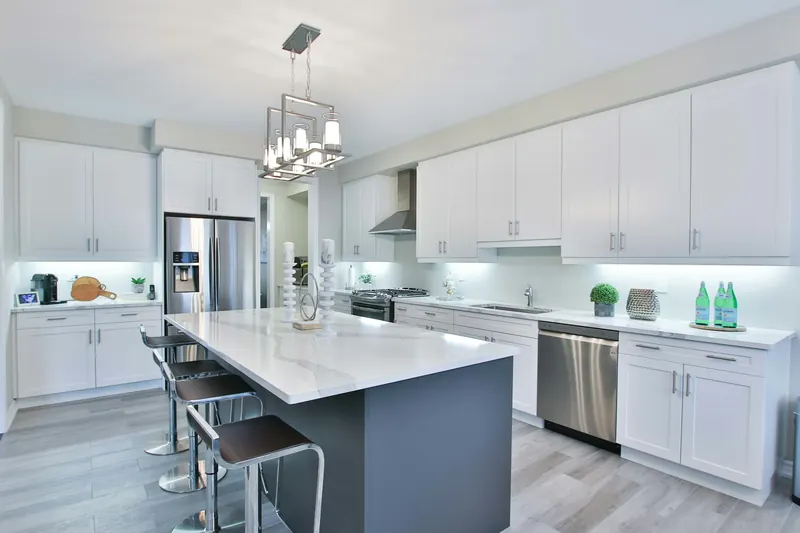 Remodeled kitchen with white cabinets, dark island and stainless appliances