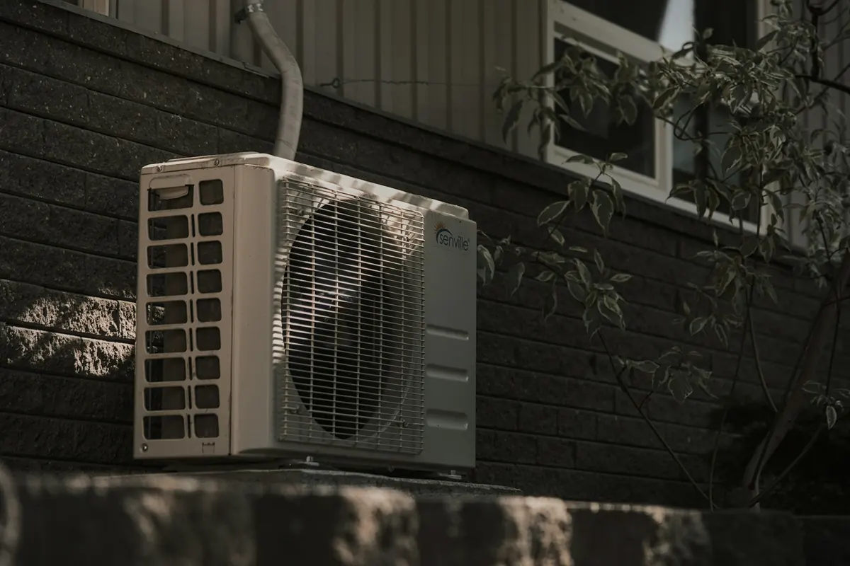 Residential AC condenser unit installed outside a brick home