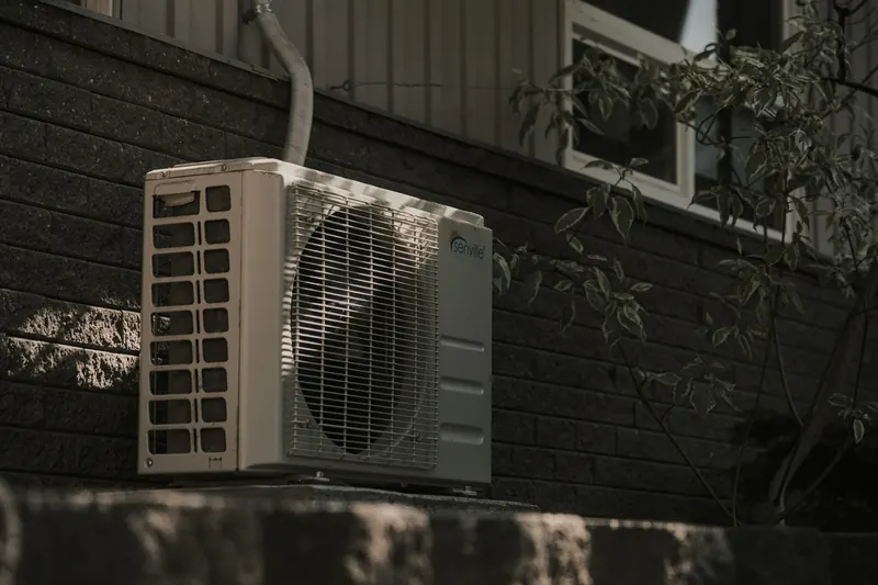 Residential AC condenser unit installed outside a brick home