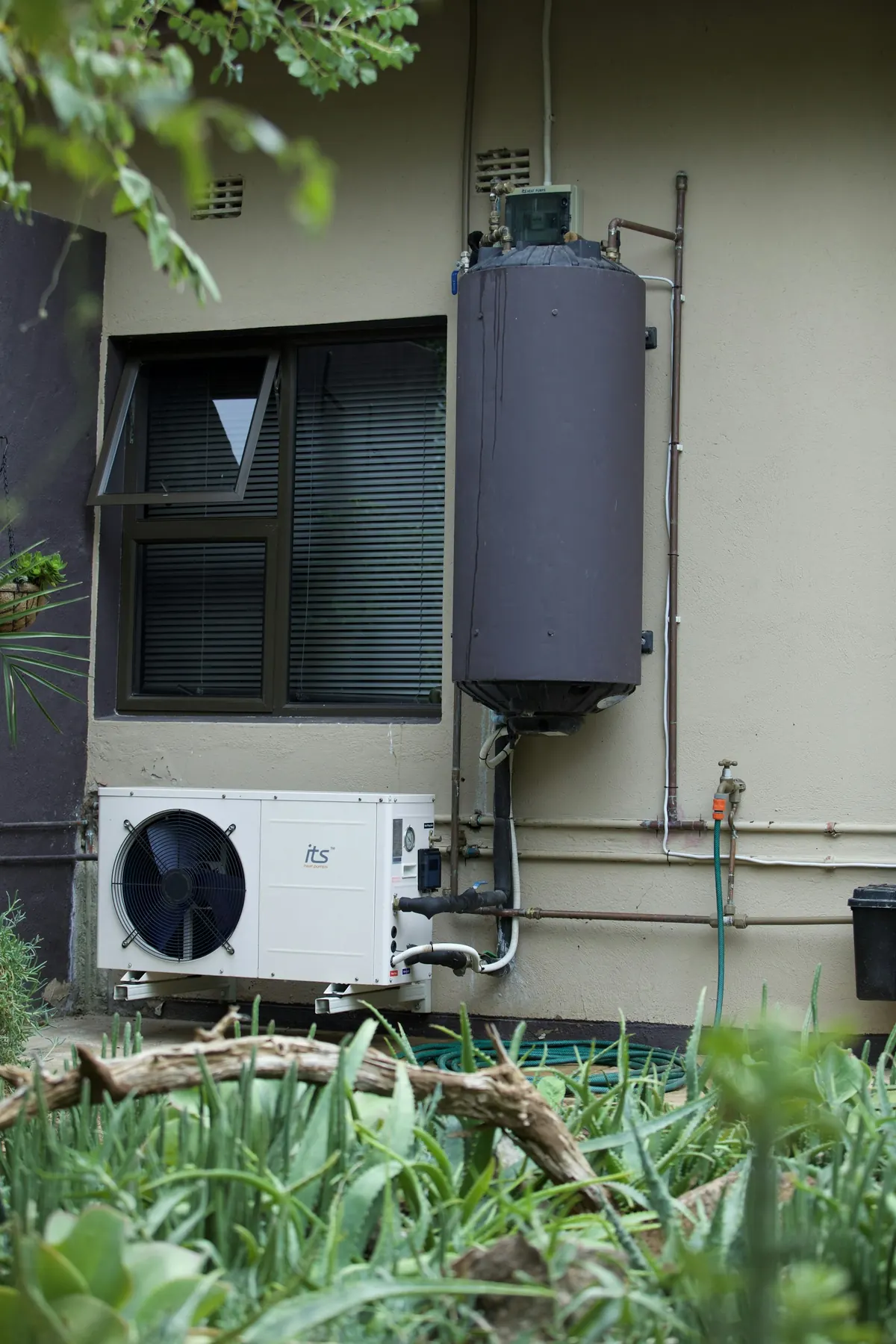 Residential water heater and heat pump installed on an exterior wall